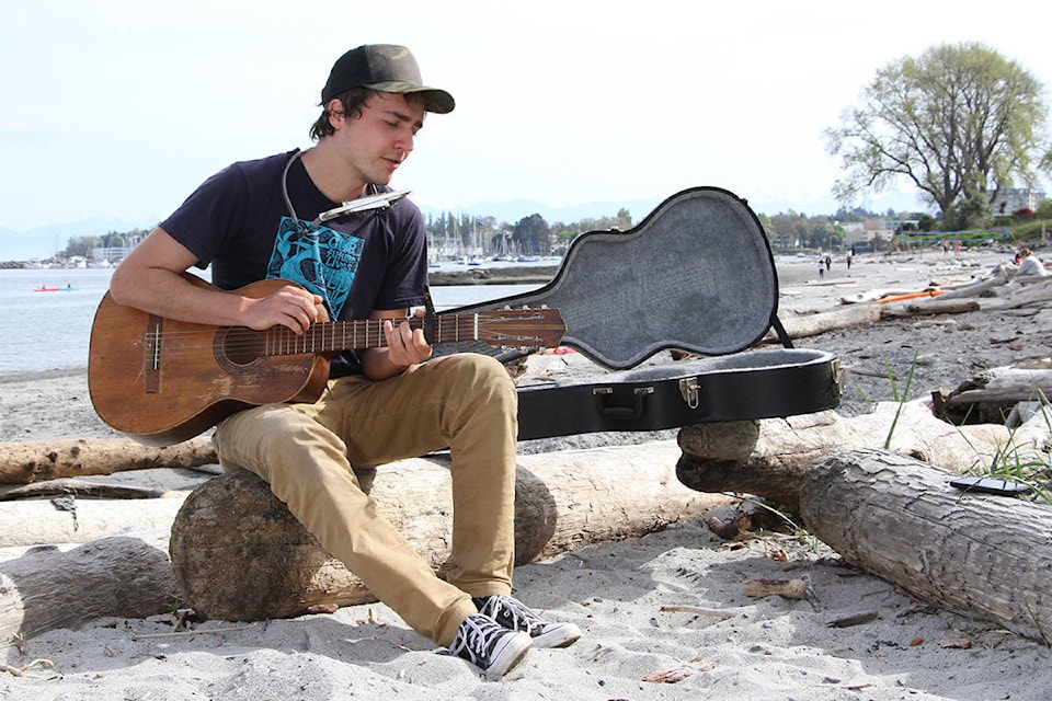 Jackson Peters picks, plays and sings on Willows Beach. Peters likes to tour parks in Greater Victoria to practice his music and enjoy the outdoors. (Christine van Reeuwyk/News Staff)