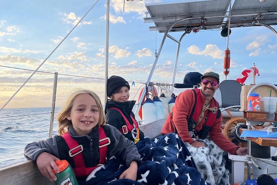 Mick Coles with his kids Thomas and Bentley (front) enjoy a beautiful evening before a night passage. (Kate Coles/Cruising Meraki)