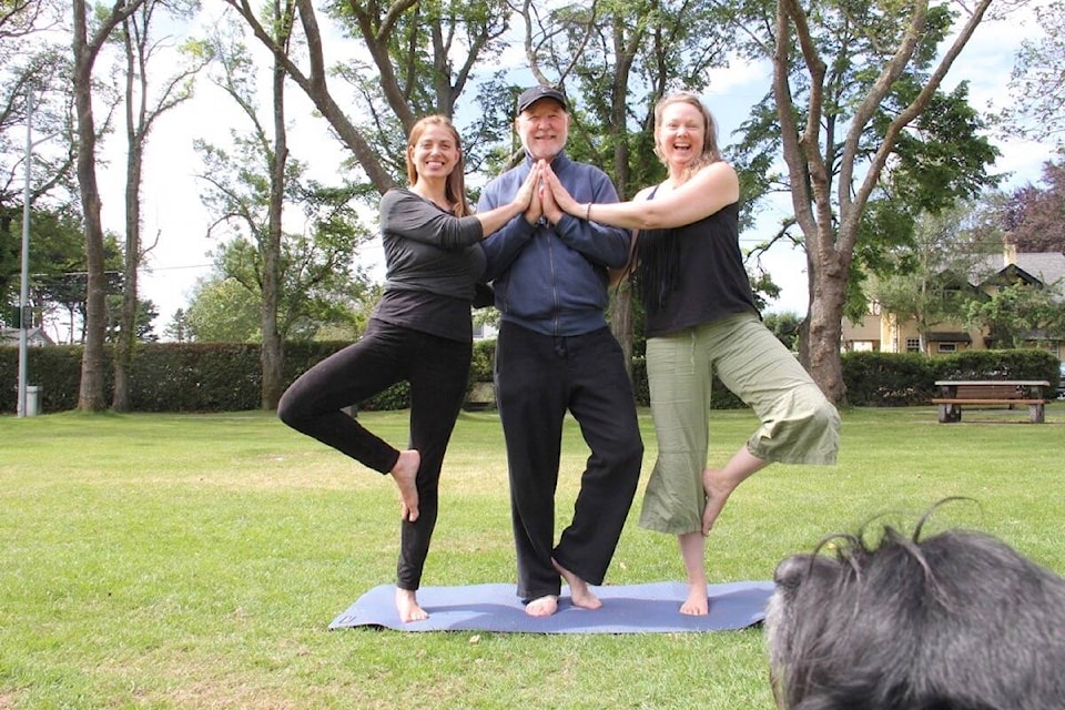 Ajna Yoga founders Jules Payne, and Michelle Schroeder flank Pete Rose as they practice yoga in Willows Park while Duncan looks on. Free yoga in the park returns to Oak Bay on July 5 and runs each Tuesday through August. (Christine van Reeuwyk/News Staff)