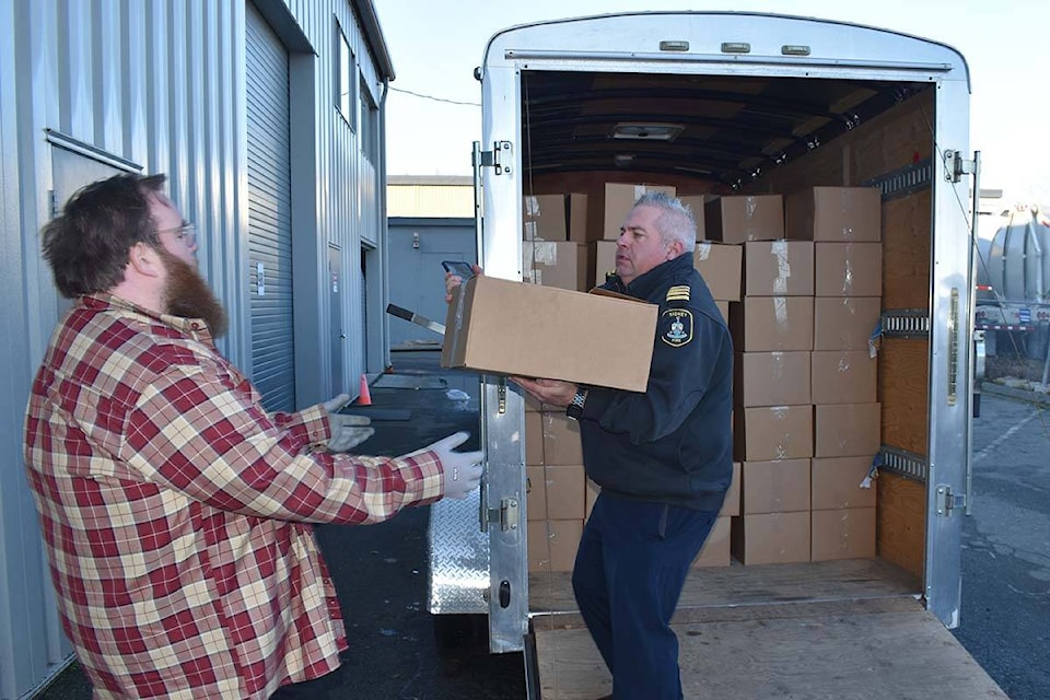 Tyson Elder, operations manager of the Saanich Peninsula Lions Food Bank, accepts one of the first boxes of donated food collected by Sidney Volunteer Fire Department from deputy chief Mike Harman Monday morning. (Wolf Depner/News Staff)