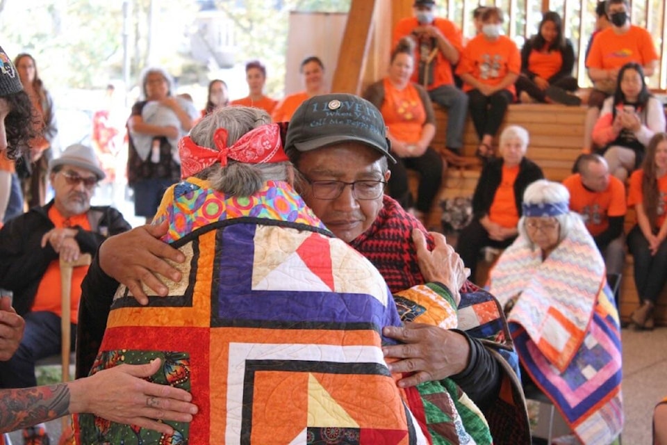 Eddy Charlie embraces Tsartlip First Nation elder May Sam after gifting her with a quilt at Na’tsa’maht, an open-sided structure inspired by Coast Salish designs, located at Camosun College’s Lansdowne campus. (Austin Westphal/News Staff)