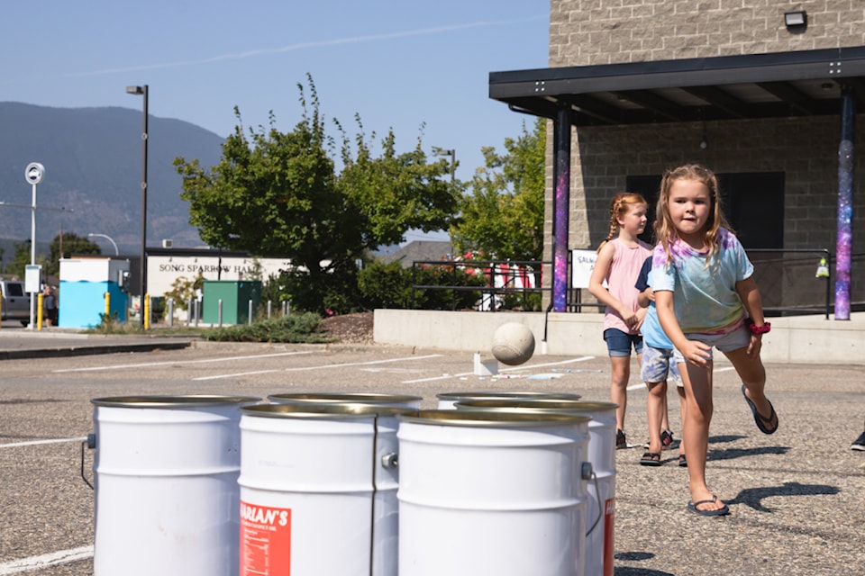 Esther Smith pitches a softball towards a bucket in one of the games outside the Salmar Grand celebration of Salmar Cinemas' 75th anniversary on Saturday, Sept. 7, 2024. 