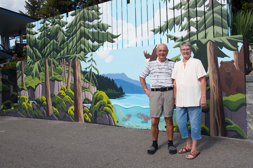 Mitch and Ellie McGaughey stand next to part of the mural recently completed outside their Raven home by local artists Becky Luth and Rachel Unger.