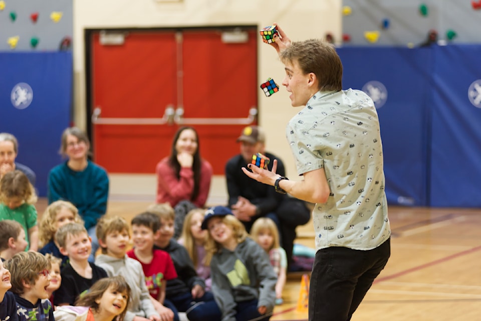 Kids keep their eyes on the cubes as Evan Johaneson, aka Evan the Juggler, solves three Rubik's Cube puzzles while juggling them during an Unplug and Play event hosted at Bastion Elementary School on Wednesday evening, Jan. 29, 2025. 