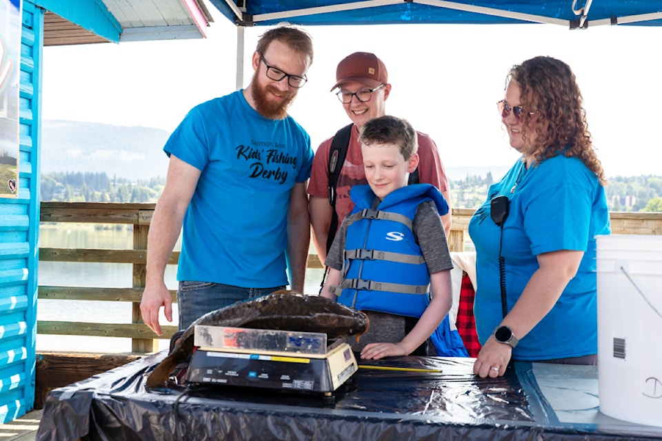 Volunteers Dustin and Alyssa Hutchinson join Erica Hummel and her son Euan Boxwell in checking out the weight of Euan's catch 㽶Ƶֱ the fish that would end up being the largest caught at the Salmon Arm Kids Fishing Derby held at the Marine Peace Park wharf on Sunday, June 15, 2025. 
