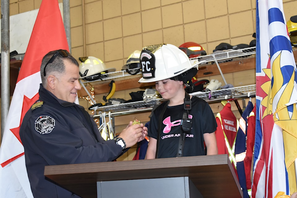 Sicamous Fire Rescue's full-time Chief Lorenzo De Arcangelis pins an official badge on Fire Chief for a Day Logan Dawson at the May 20 crew practice.