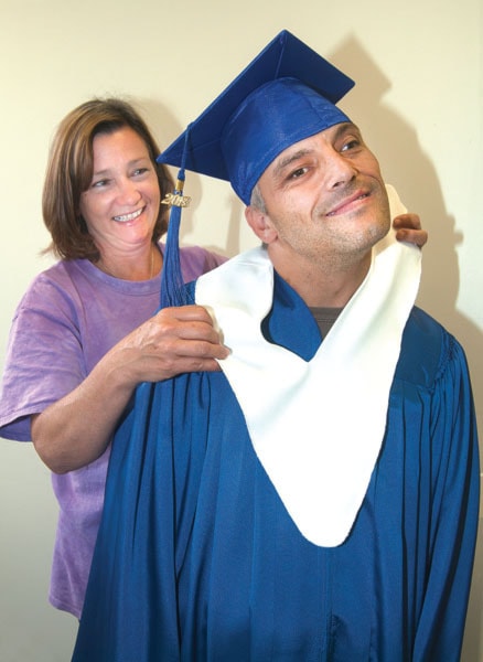 Education support worker Gerri Kiy helps Jason Cadeau with his graduation gown.