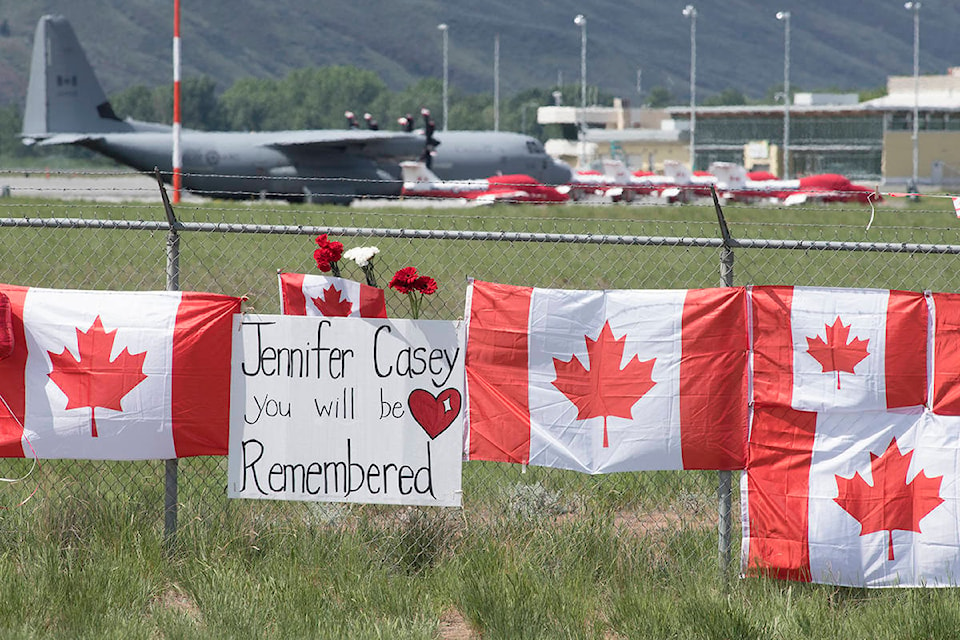 The Canadian Forces Snowbirds jets are seen in the background as Canadian flags are attached to the fence at the Kamloops airport in Kamloops, B.C., Monday, May 18, 2020. Capt. Jenn Casey died Sunday after the Snowbirds jet she was in crashed shortly after takeoff. The pilot of the aircraft is in hospital with serious injuries. THE CANADIAN PRESS/Jonathan Hayward