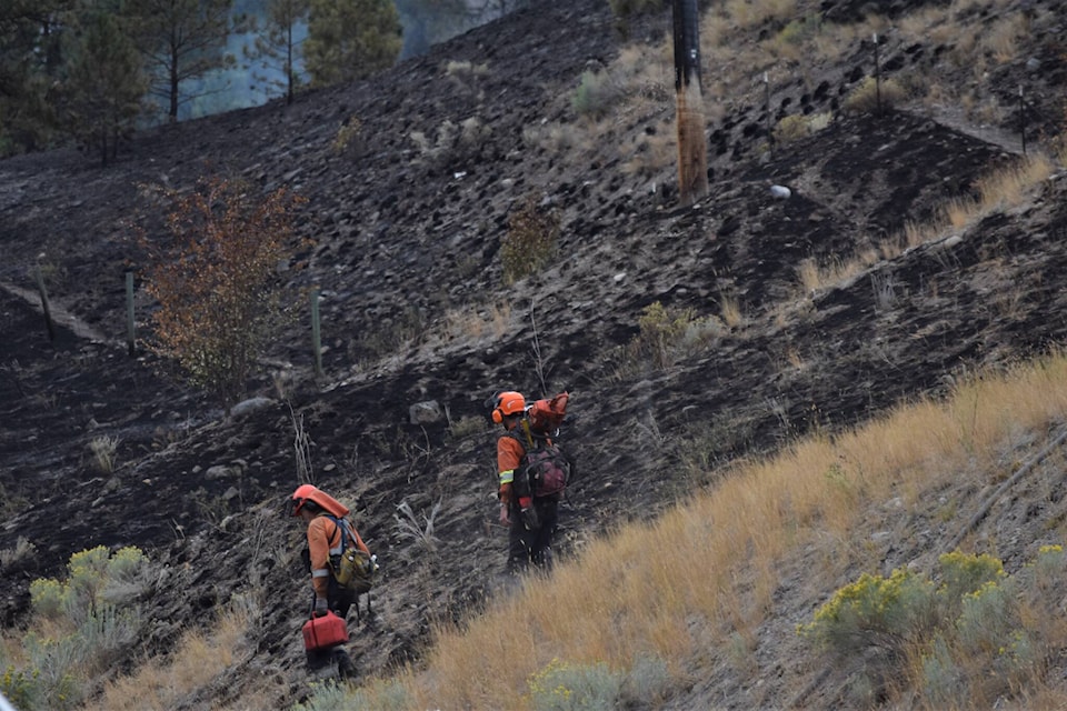 Two BC Wildfire firefighters coming down the slope of the Hedges Butte wildfire. (Brennan Phillips - Western News)