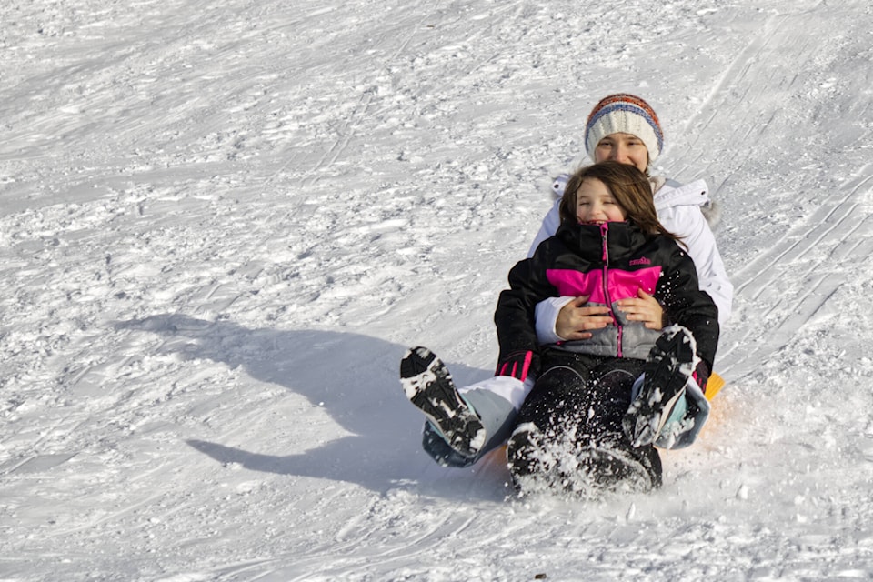 Jessica Lewis holds her daughter June as they sled down the hill at South Broadview Elementary in Salmon Arm on Feb. 5, 2022. June was celebrating her upcoming seventh birthday by hosting a sledding party for her friends. (Zachary Roman/Salmon Arm Observer)