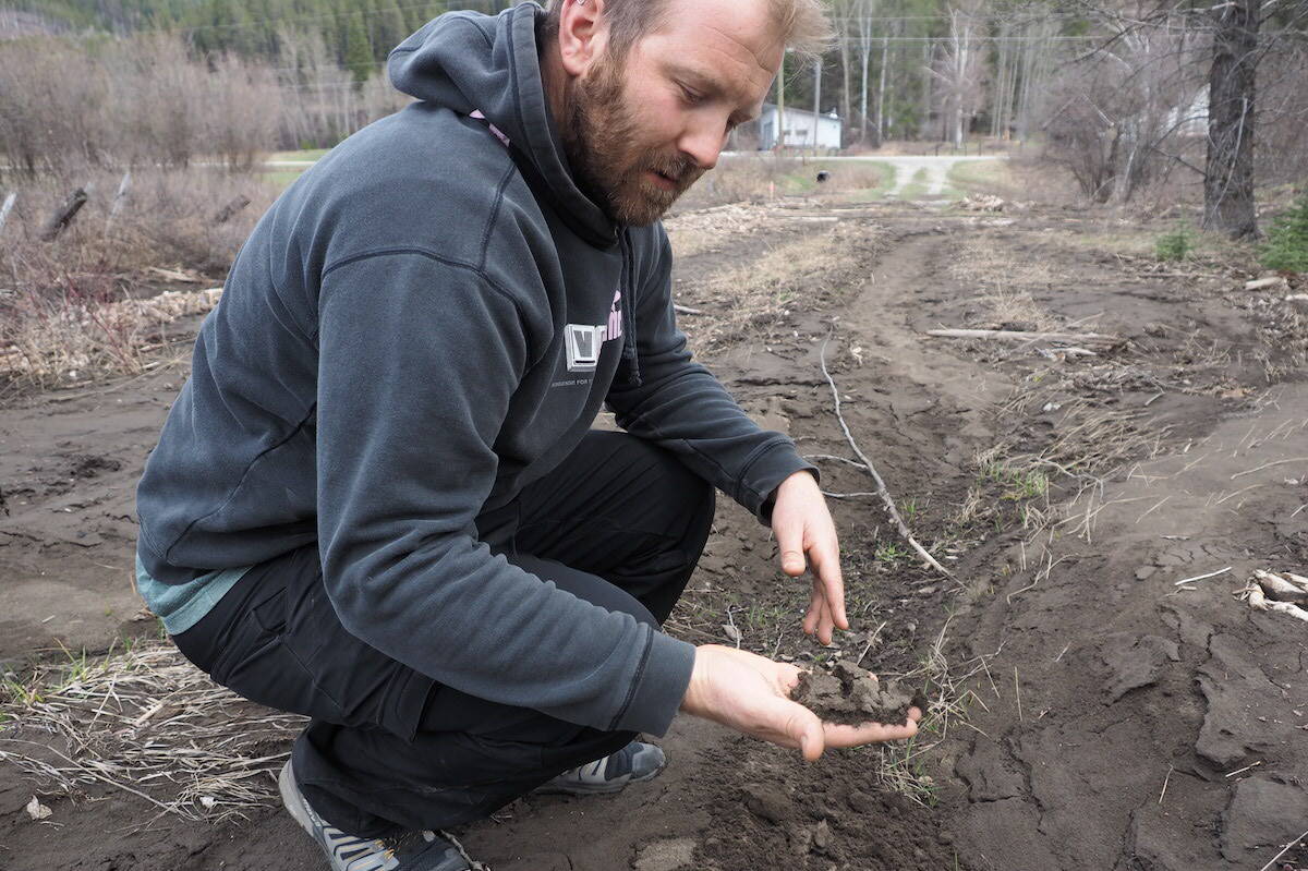 Thomas Bravais with a handful of the silt covering his land. (Scott Tibballs / The Free Press)