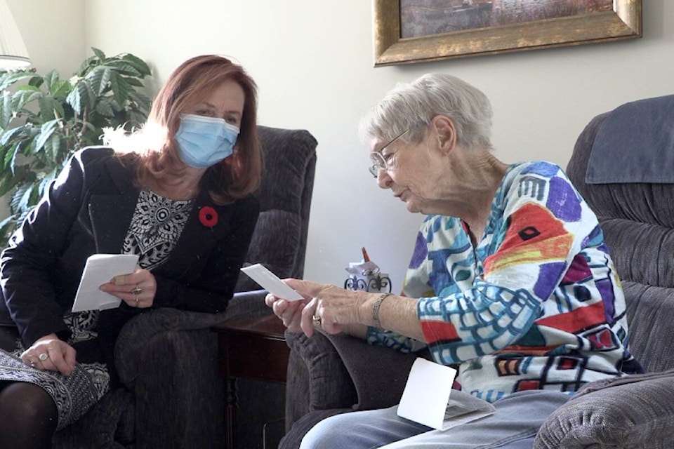 Mickey sits with her niece Heather looking at photographs from her time working in Ontario during the Second World War (Brittany Webster - Capital News)