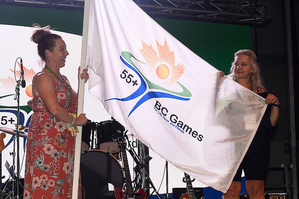 Abbotsford 2023 55+ BC Games president Mary Boonstra (left) passes the flag to Salmon Arm 2024 55+ BC Games president Debbie Cannon on Friday, Aug. 25, 2023. (55+ BC Games photo team)