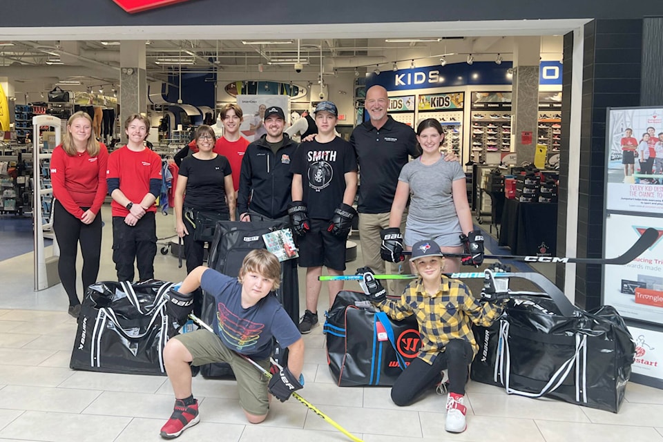 Salmon Arm SportChek employees Peyton Major, Colby Geiger, and Nate Evanishen join assistant manager (third from left) Trish Hanson and (rest of back row) Salmon Arm Minor Hockey Association’s manager of hockey operations Cole Slaney, Pryce Williams, Ian Gray, Rozalynn Williams and (front row) Everett and Daxton Williams as the children shop for new hockey gear after theirs was lost in the Bush Creek East wildfire. (Cole Slaney-SAMHA)