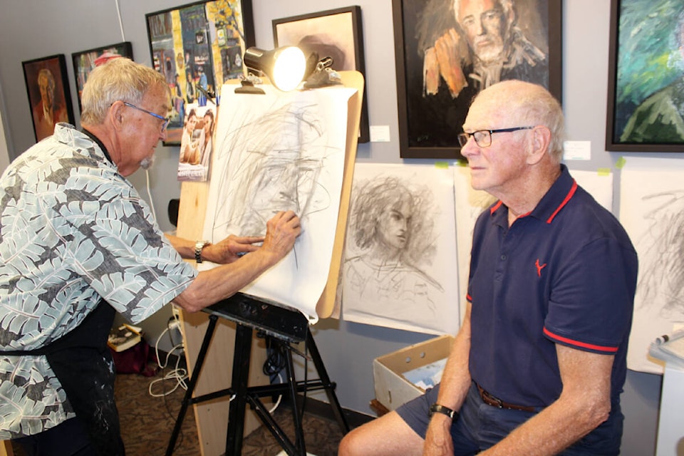 Art Carlyle at work on a portrait of longtime friend Ernie Hutton at Rainforest Arts. (Photo by Don Bodger) 