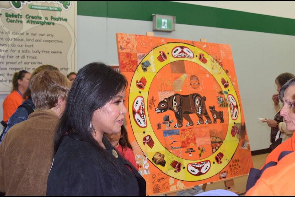 Coast Salish artist Dahlila Charlie talks with onlookers about the Art of Reconciliation mosaic she designed at the Greenglade Community Centre. (Brendan Mayer/News Staff) 