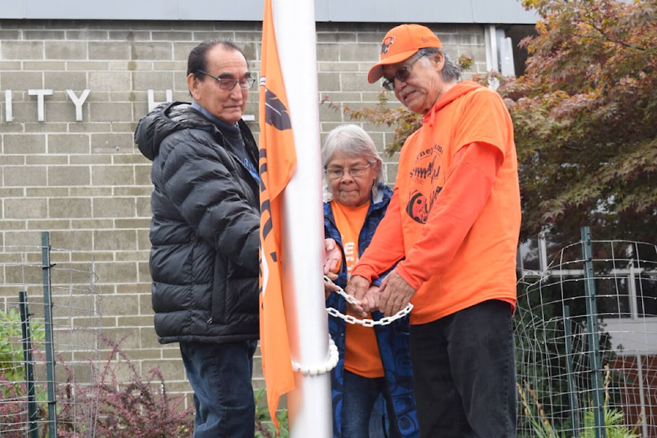 Residential school survivors raise the “Every Child Matters” flag outside of Port Alberni City Hall on Monday, Sept. 25. (ELENA RARDON / Alberni Valley News) 