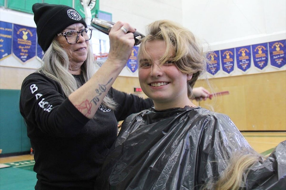 Grade 9 student Lizzy Lindsay loses a head of thick hair – as described by barber Marilyn Bishop of Avenue Barber – during the Sept. 27 Cops for Cancer fundraiser at Oak Bay High. (Christine van Reeuwk/News Staff) 
