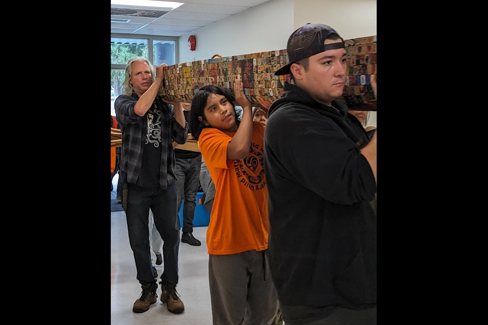 Carl Stromquist (left back), Koi Elkins-Andrews (middle), and Jordan Crowell (right front) carrying the Project Heart Canoe into Silver Creek Elementary School. (Pattie Desjardins/Hope Standard) 
