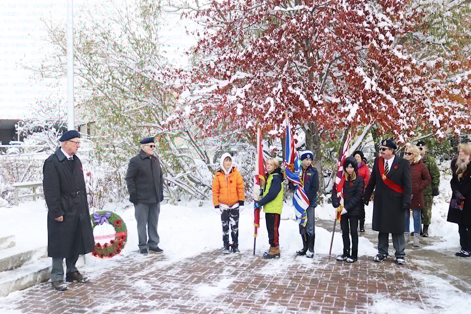 Bill Carr of the Royal Canadian Legion (left) stands before student flag bearers Alex Banman-Clark, Luke Buchanan and Maren Jones at the second annual No Stone Left Alone ceremony at the Coldstream cenotaph Tuesday, Nov. 8, 2022. (Brendan Shykora - Morning Star) 