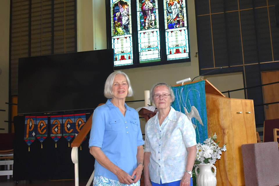 Penticton United Church council chair Marion Kozier and longtime church member Fern Gibbard stand in front of the pulpit and many stained glass windows inside the 95-year-old church that is closing. (Monique Tamminga Western News) 