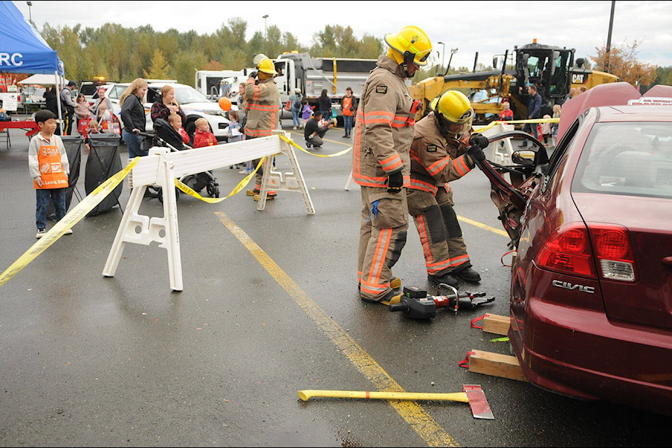 People of all ages came out to the Chilliwack Safety Fair in the parking lot of Home Depot on Saturday, Oct. 14, 2023. Above, members of the Chilliwack Fire Department remove a car door after using the Jaws of Life during a demonstration. (Jenna Hauck/ Chilliwack Progress) 