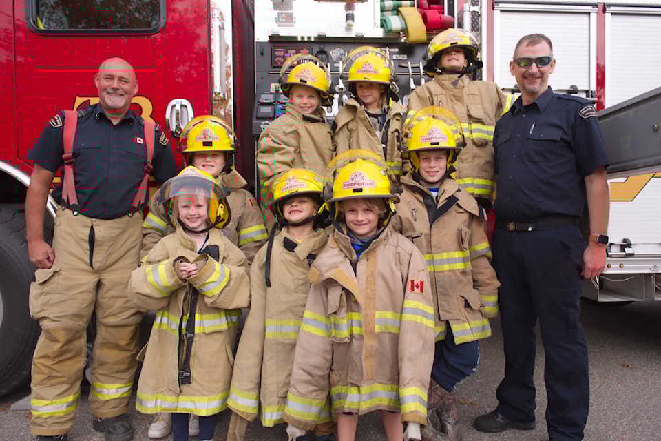 Salmon Arm Fire Department Fire Chief Brad Shirley and Lt. Tyler Stevenson pose for a photo with their young Fire Chiefs for a Day at Fire Hall 2 on Thursday, Oct. 12, 2023. (Lachlan Labere-Salmon Arm Observer) 