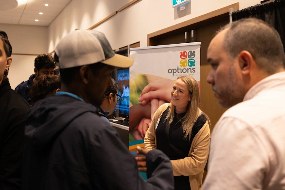 A representative from Options Community Services speaking to attendees at Black Press Career Fair at Civic Hotel in Surrey on Friday, Oct. 13, 2023. (Photo: Anna Burns) 
