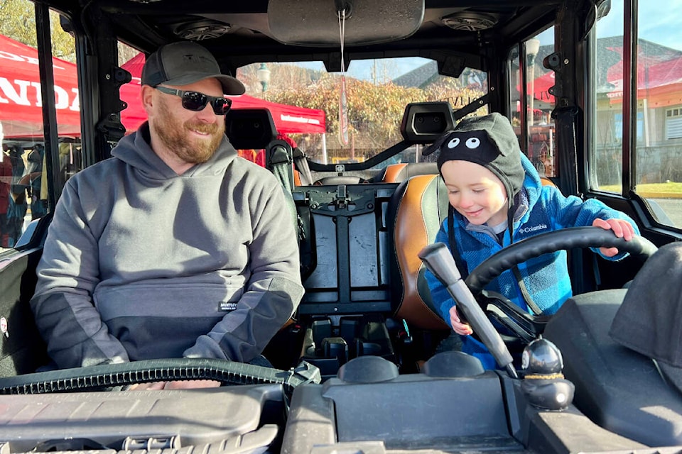 Williams Lake Powder Kings Snowmobile Club director Braden Fontaine attends Snow Fest Sunday (Oct. 29), giving his son Ajay a chance to check out a side-by-side on display. (Angie Mindus photo - Efteen) 