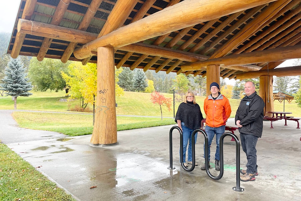Mary Thurow, granting coordinator for Williams Lake Community Forests, from left, Guy Ridler, Streets for All Williams Lake volunteer, and Rob Warnock, city of Williams Lake director of municipal services, stand next to one of the new bike racks installed in the city thanks to a grant from the community forest. This rack is in the covered seating area in Boitanio Park to provide a secure, covered spot for cyclists doing activities in the park. (Ruth Lloyd photo - Efteen) 