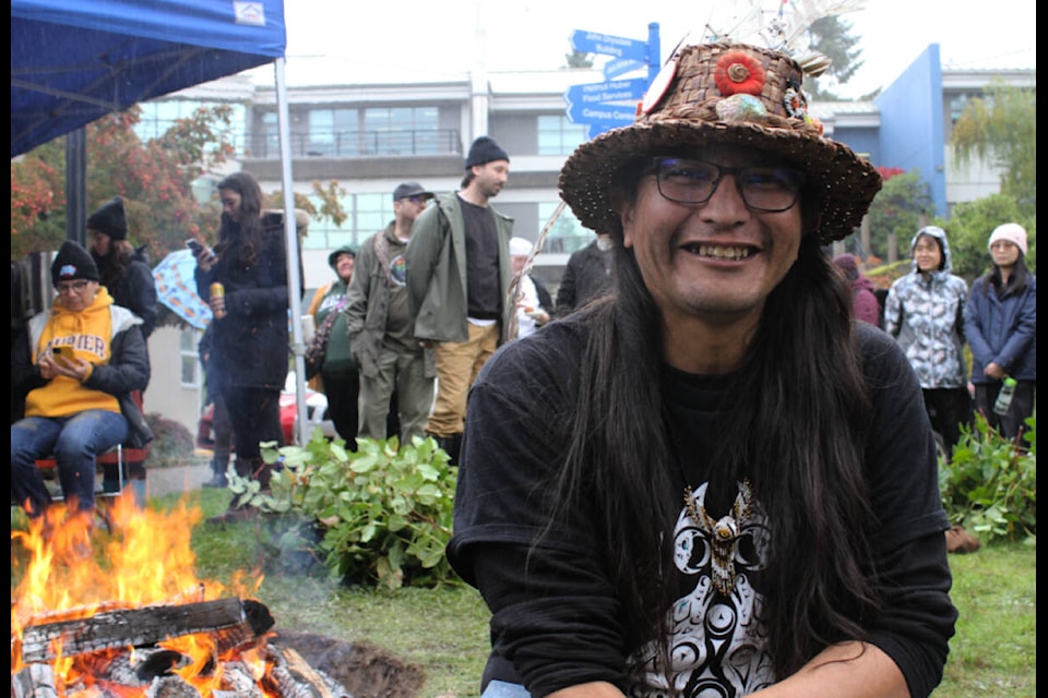 J.B. Williams of the Tsawout First Nation in front of the fire for traditional Coast Salish pit cook hosted by the Eye Sqa’lewen and Camosun College at the Interurban Campus. (Ella Matte/News Staff) 