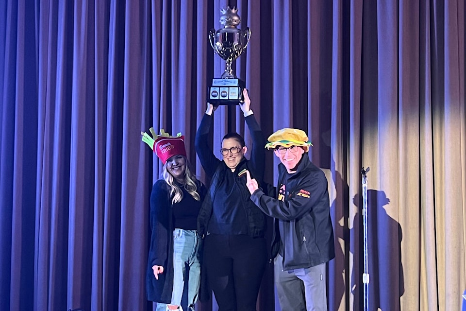 Deena Derksen (centre), chef and manager at Diner on Six, triumphantly lifts the 2023 Golden Burger Challenge trophy after her burger creation was named the winner of the competition at the Vernon Towne Theatre Tuesday, Nov. 7, 2023. (Brendan Shykora - Morning Star) 