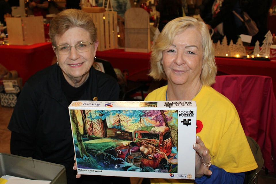 Pam Craig and Cheryl Hamilton of the Arrowsmith Rotary Club display the puzzle that they are selling as a Rotary fundraiser. The image is from McLean Mill and was created by artist Shelley Penner during the Landmarks exhibit at The Grove Art Gallery earlier in 2023. The puzzles will be available at Flandangles on Nov. 15 for Moonlight Madness. (SONJA DRINKWATER PHOTO) 