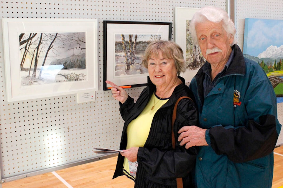 Kathleen Spiess (left) purchased a painting from David Clark called Winter Sun at the Garibaldi Art Club annual Fall Art Show on Nov. 18. (Brandon Tucker/The News) 
