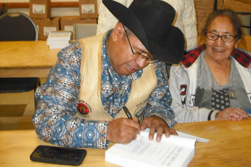 Xeni Gwet’in Chief Roger William, signs a copy of the book for his mother Eilleen William, while co-author Lorraine Weir looks on. (Sage Birchwater photo) 