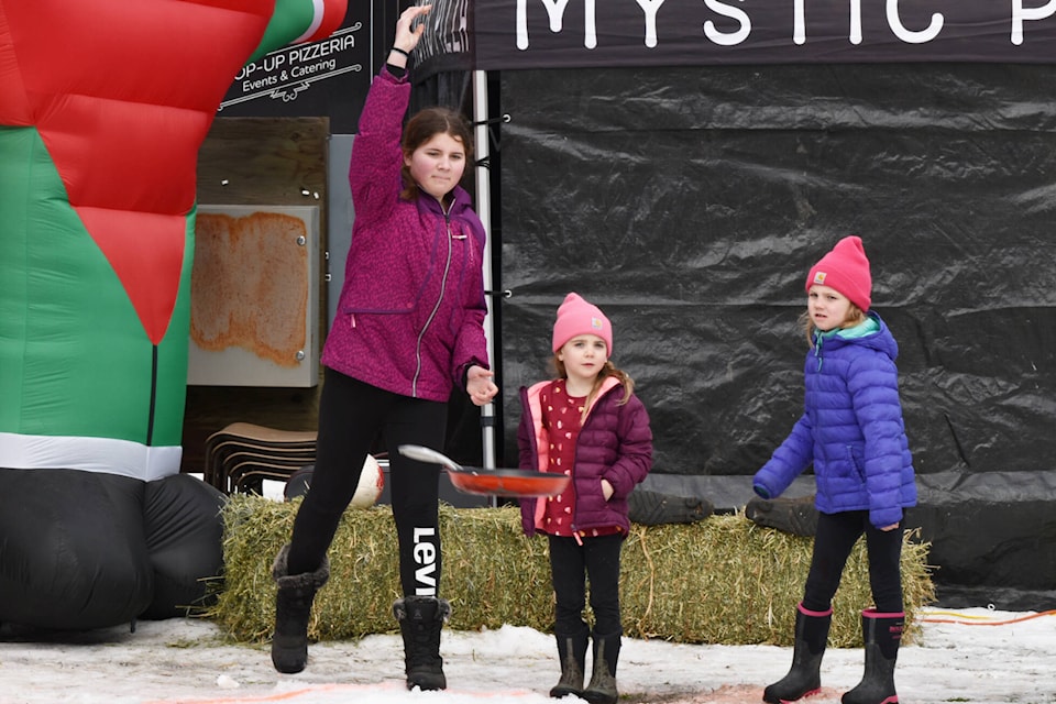 Bree Heinrich throws her winning frying pan toss, watched by her competitors Claire and Julia Wycherley, at Salmon Arm’s Winter Fun Fest held Feb. 18, 2023. (Rebecca Willson/Salmon Arm Observer) 
