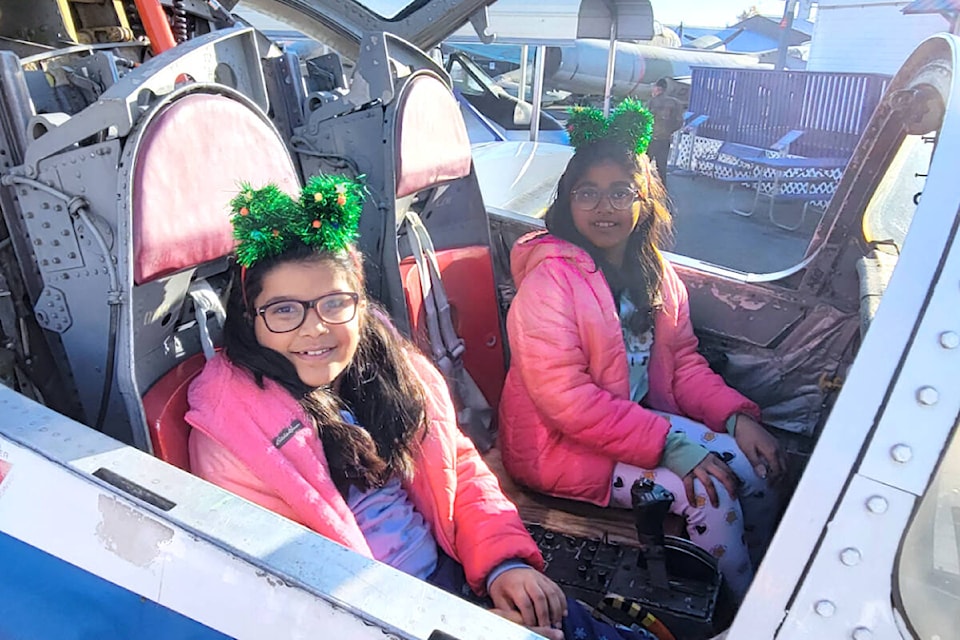 Above, sisters Ananya, nine, and Aradhya, seven, visited the Canadian Museum of Flight for its second annual free Christmas event on Saturday, Nov. 25.  Far left, Brenda Radstaak (left) helped organize the event, where Santa took photos with visitors. Left, volunteers of the Canadian Museum of Flight helped visiting kids craft aviation ornaments. (Kyler Emerson photos/91ԭ Advance Times) 