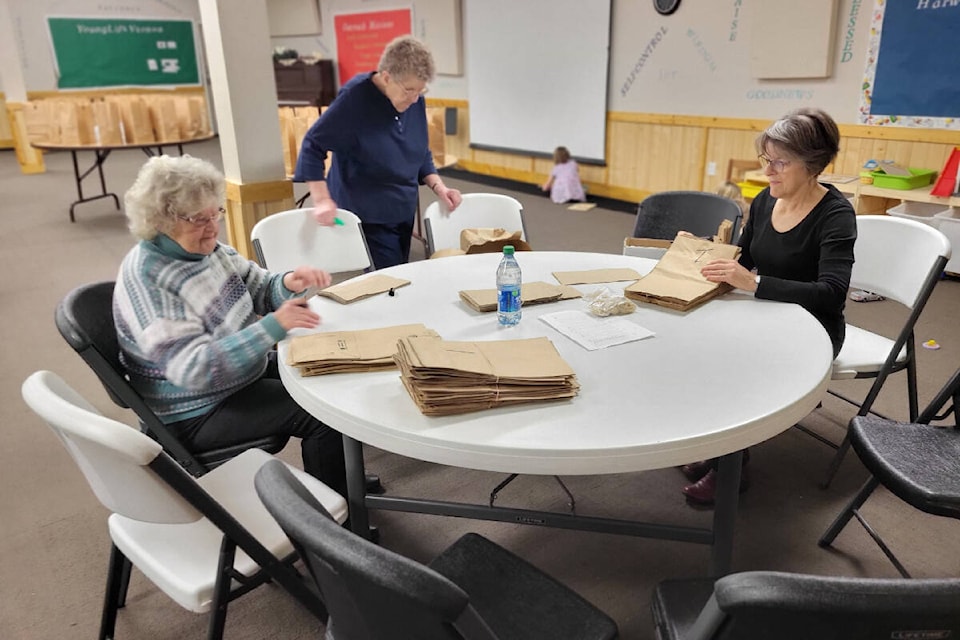 Faith Baptist Church Harwood/Seaton Breakfast Program volunteers June Hock (elft) and Sheila Robinson (right) number bags for delivery under the watchful eye of program coordinator Anne Rea. (Roger Knox - Morning Star) 