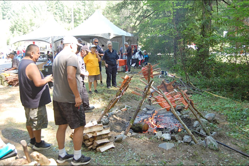 Attendees at the July 2023 First Fish Ceremony near Spuzzum watch fresh salmon roasting on the ceremonial fire. (Photo credit: Barbara Roden) 