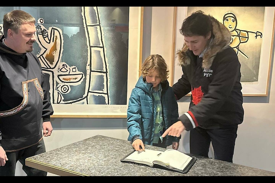 Prime Minister Trudeau points to the spot in the legislative assembly guest book where he has signed in Inuktitut syllabics, so that his son Hadrian can copy them while Premier P.J. Akeeagok looks on. Kira Wronska Dorward/ӯv3. 