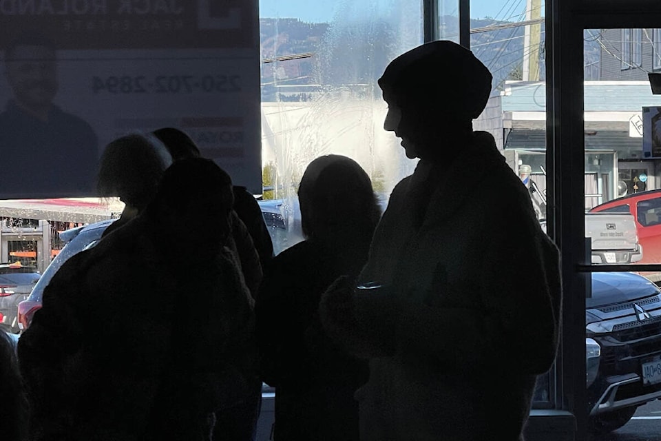Kama Money, right, is silhouetted in the window of a building on Argyle Street chatting to people waiting to see holistic service providers during a fundraiser in January 2024. (SUSIE QUINN/ Alberni Valley News) 