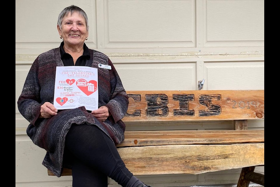 Cowichan Brain Injury Society executive director Chris Rafuse sits outside on a bench that was one of Men’s Shed passion projects. She holds up the flyer for their burger and beer fundraiser that will take place at the White Spot in Duncan on Feb. 13 from 6:30 to 8:30 p.m. (Chadd Cawson/Citizen) 