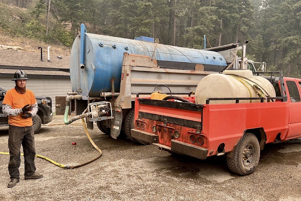 Jeremy Spooner with two of the Spooner fire trucks in east Lee Creek. (Jennifer Spooner photo) 