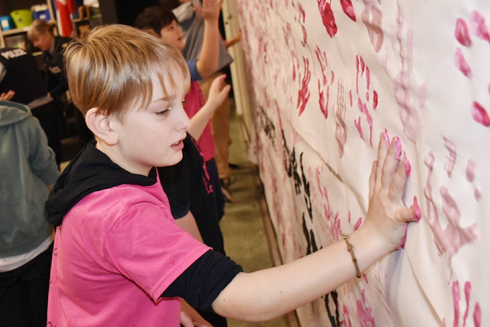 Ayden, Grade 5, at Pitt Meadows Elementary, adds his hand print to the banner. (Colleen Flanagan/The News) 