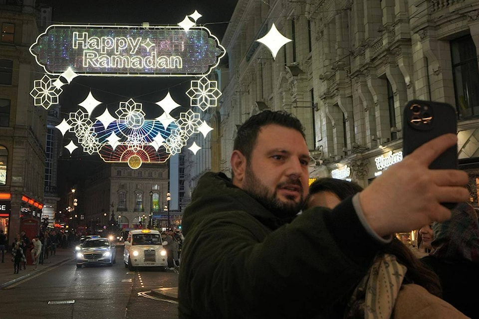A man takes a selfie in front of the Ramadan lights installation to celebrate the upcoming start of Ramadan, at Piccadilly Circus in London, Thursday, March 7, 2024. This will be the 2nd year that Ramadan Lights have been installed in the heart of Central London. (AP Photo/Kirsty Wigglesworth) 