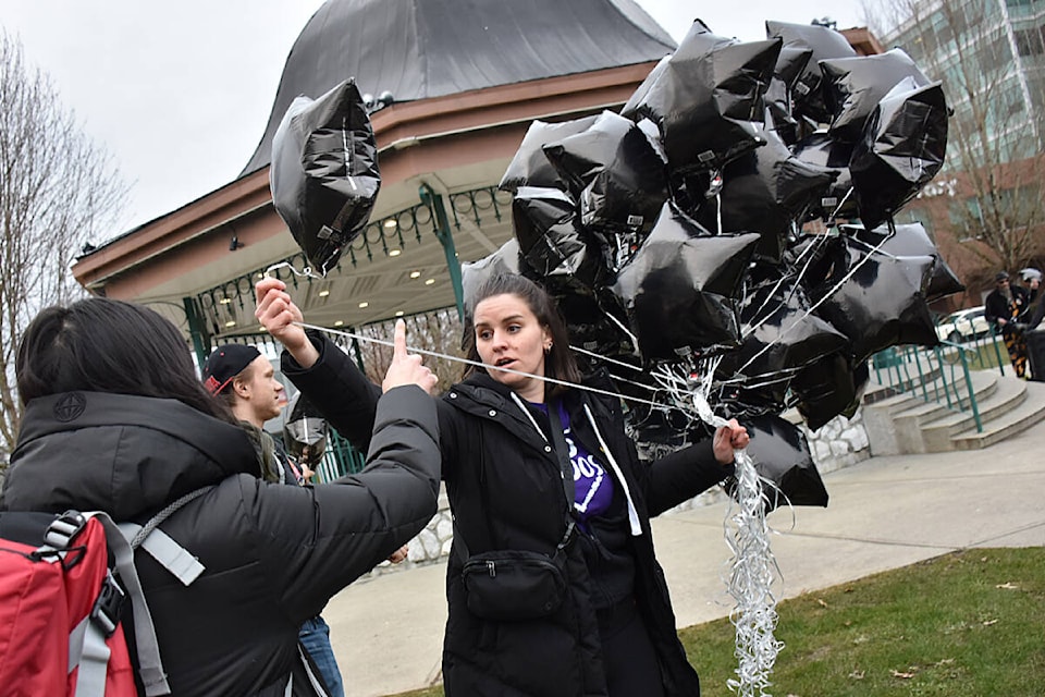 Jerrica Hackett, organizer and project coordinator with Stop Overdose Ridge Meadows, STORM, passes out black balloons before a memorial walk downtown Maple Ridge. (Colleen Flanagan/The News) 