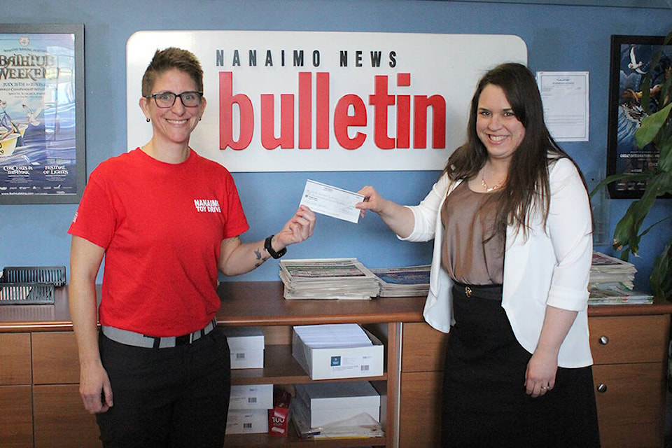 Krista Simpson, vice-chairperson of the Great Nanaimo Toy Drive, left, is presented with a $1,750 donation from Coins for Kids, represented by Sharon Sakaki, Nanaimo News Bulletin ad controller, earlier this month. The money came from proceeds from the News Bulletin’s charitable drive. (News Bulletin photo) 