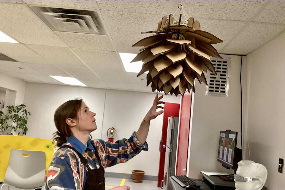 Kailey Allan shows a chandelier model built from cardboard. 