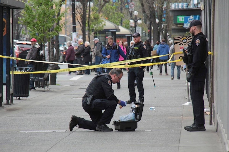 A VicPD officer collects evidence in one of three cordoned off sidewalks in downtown Victoria on the morning of April 15. (Christine van Reeuwyk/News Staff) 