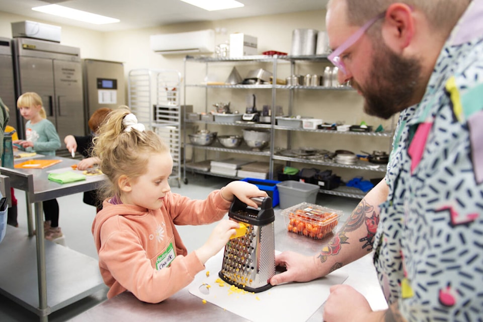 Will Miller looks on as Charlotte grates some cheese during a Little Chefs class at Zest Commercial Food Hub on Tuesday, April 9, 2024. (Lachlan Labere-Salmon Arm Observer) 